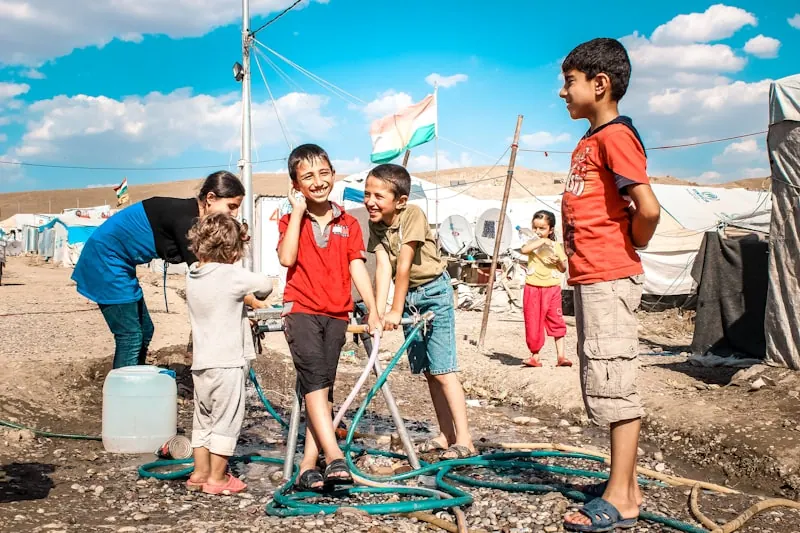 Children gathered around a community water point receiving support