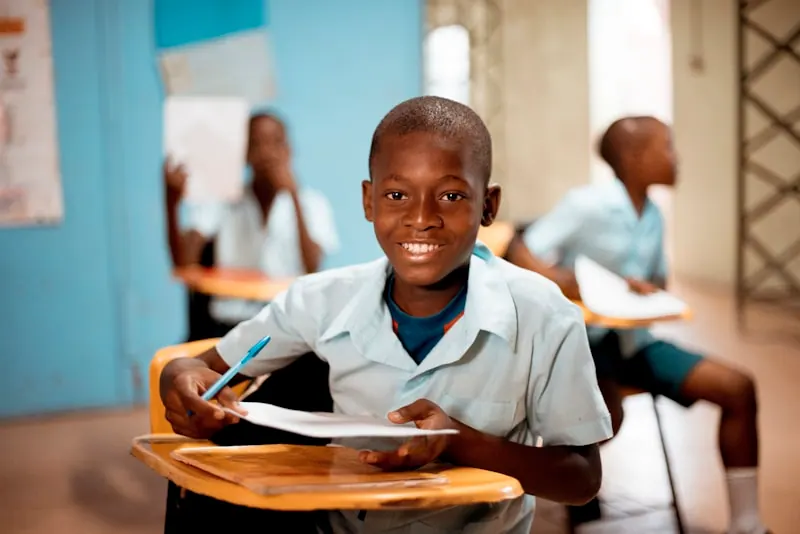 Student holding school materials, showing direct support reaching learners