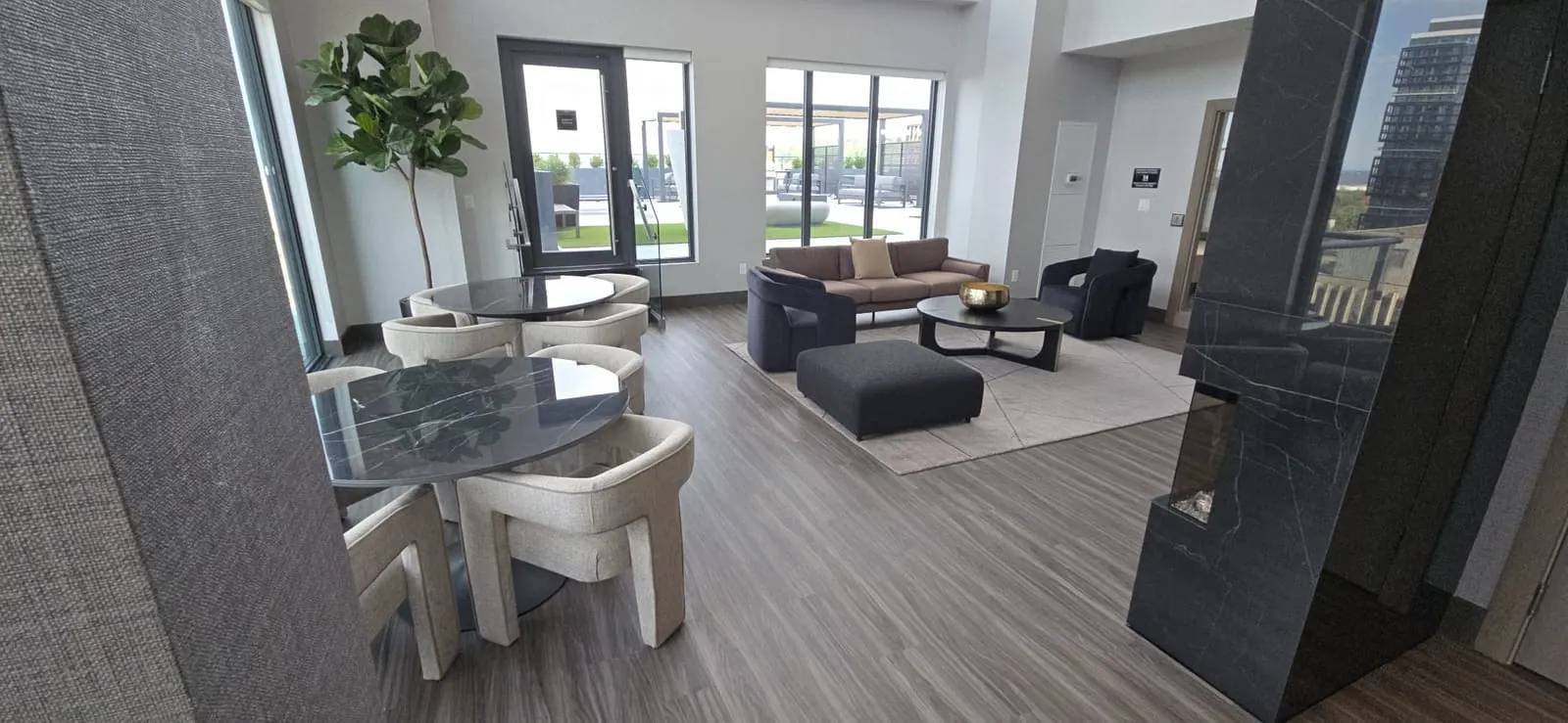 Indoor venue lounge with dining and sofa areas behind windows that open onto the rooftop terrace.