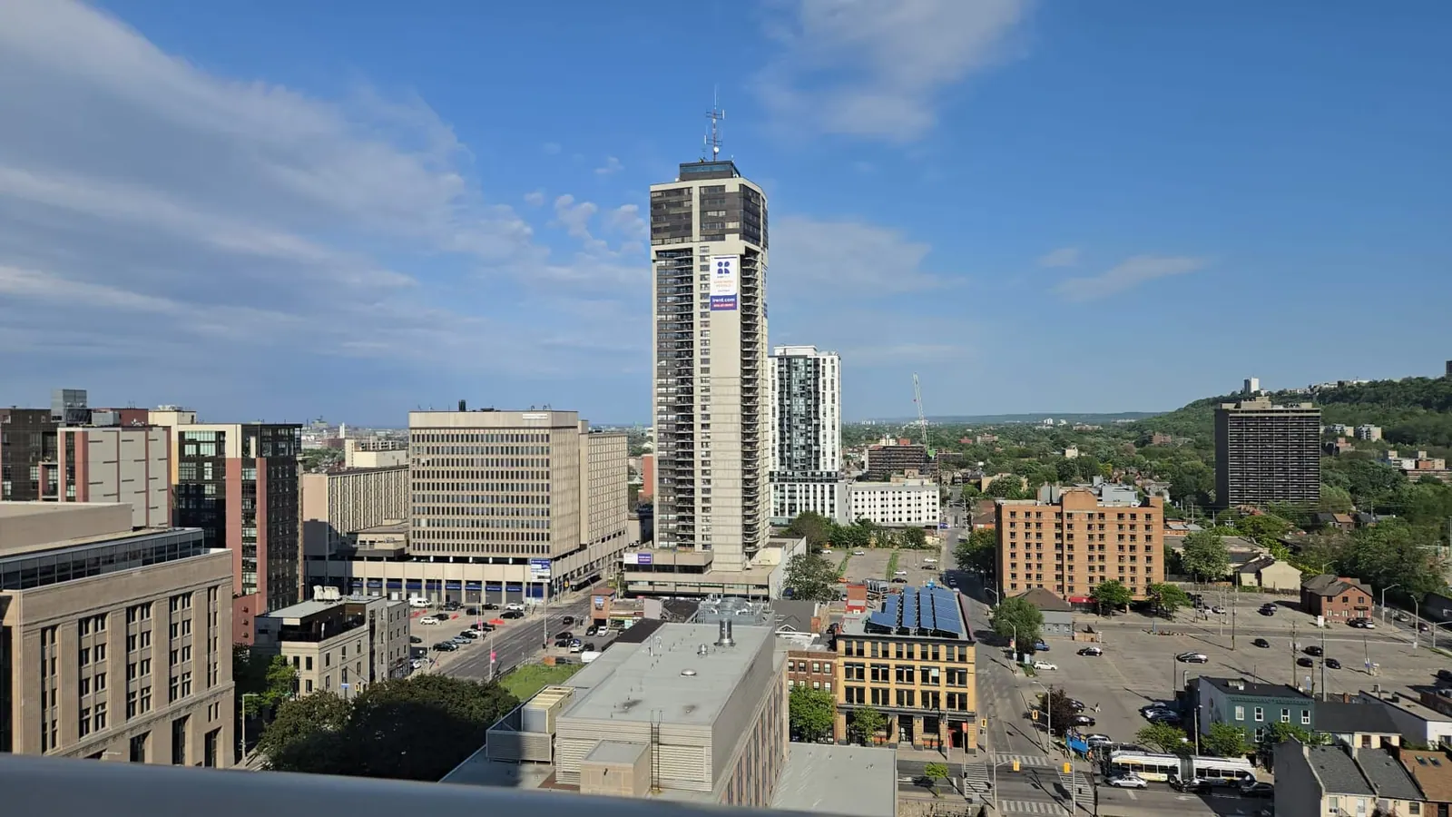 Downtown skyline from rooftop level with a landmark tower centred and green hills along the horizon.